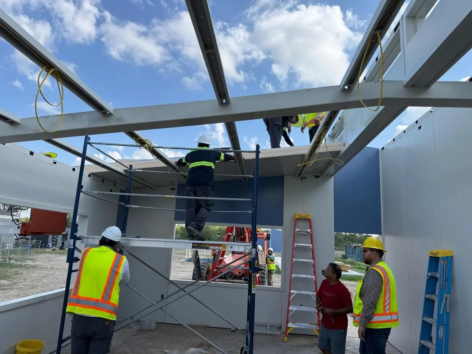 Crew setting roof panels onto the steel purlin structure