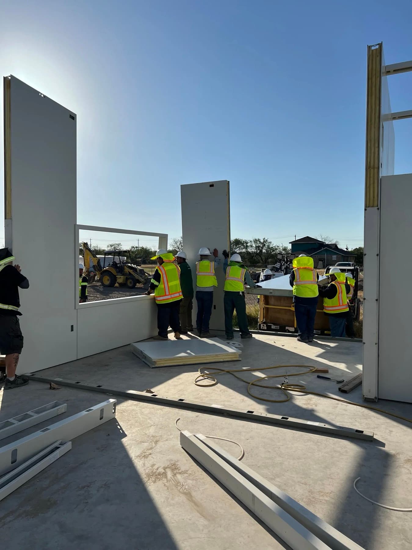 Crew standing engineered wall panels upright on the foundation slab